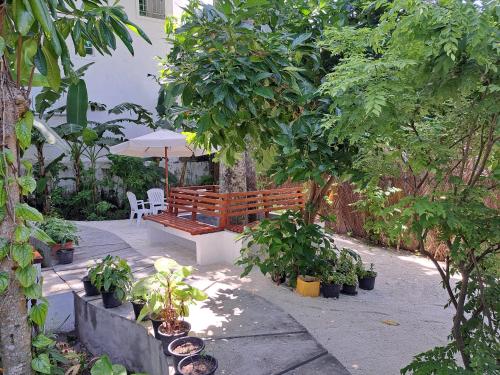 a wooden bench with an umbrella in a garden at Shams Thoddoo in Thoddoo