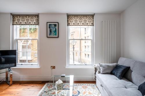 a living room with a couch and two windows at Central Stays at Liverpool Street in London