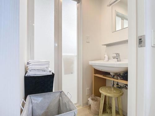 a white bathroom with a sink and a stool at キュリナリーBed and Art in Hamamatsu