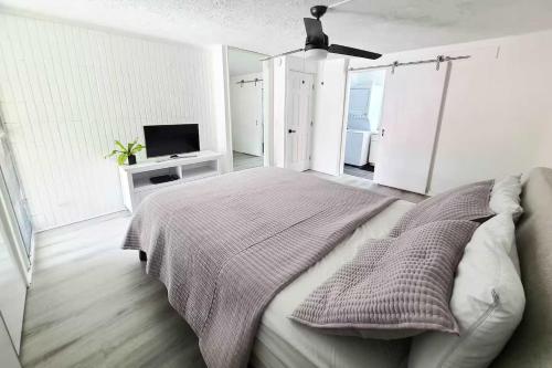 a white bedroom with a bed and a television at Beachfront Condo with Ocean View in Hauula