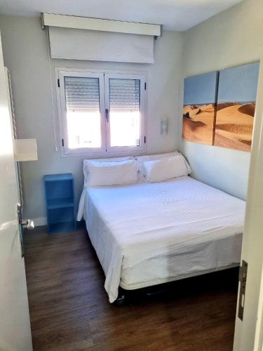 a bedroom with a bed with white sheets and two windows at Hotel Apartamento Bajamar in Las Palmas de Gran Canaria