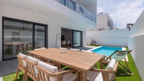 ein Esszimmer mit einem Holztisch und Stühlen sowie einem Pool in der Unterkunft Villa Aroeira with Pool by LovelyStay in Aroeira