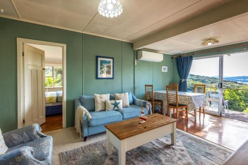 a living room with a blue couch and a table at Splashing Tūi Cottage in Waiheke Island