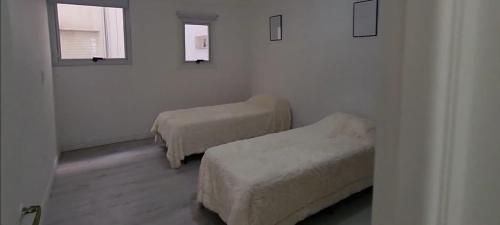 Habitación con 2 camas y reposapiés en Departamentos Bariloche, en San Carlos de Bariloche