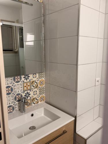 une salle de bain blanche avec un lavabo et un miroir dans l'établissement Studio Plage du cap Rousset, à Carry-le-Rouet