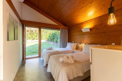 a bedroom with two beds and a large window at Bagoada Cabin - Sunset Vista - uChill in Vila Nova de Cerveira