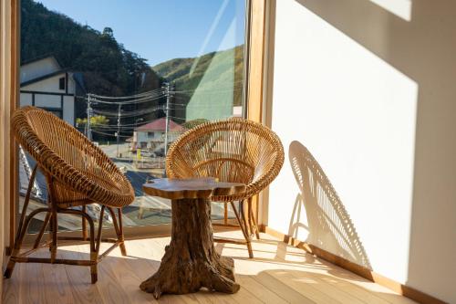a table and chairs on a balcony with a window at Kaido Nomad CoLiving in Yuzawa