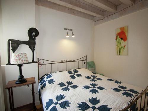 a bedroom with a bed with a blue and white comforter at Very nice cottage with studio on a domain with heated pool in Roussines
