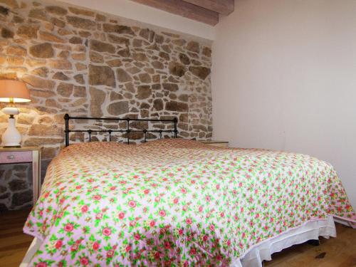 a bed in a room with a stone wall at Very nice cottage with studio on a domain with heated pool in Roussines