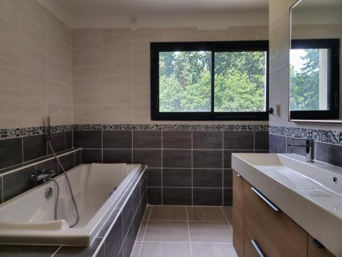 a bathroom with a tub and a sink at Les Quatre Baies in Guichen