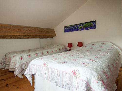 a bedroom with two beds with white sheets and red lamps at Very nice cottage with studio on a domain with heated pool in Roussines