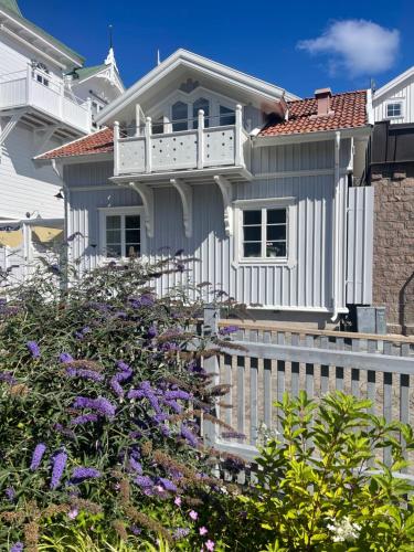a white house with a white fence and purple flowers at Marstrand in Marstrand