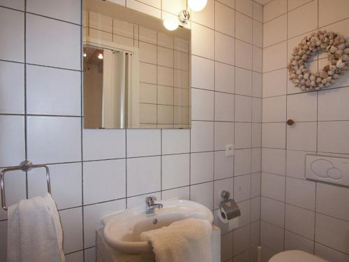 a white tiled bathroom with a sink and a mirror at Very nice cottage with studio on a domain with heated pool in Roussines