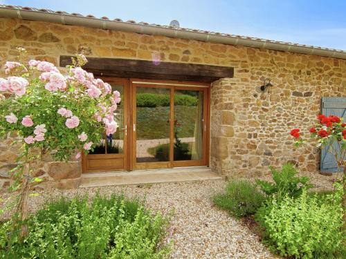 a wooden entry door to a stone building with flowers at Very nice cottage with studio on a domain with heated pool in Roussines