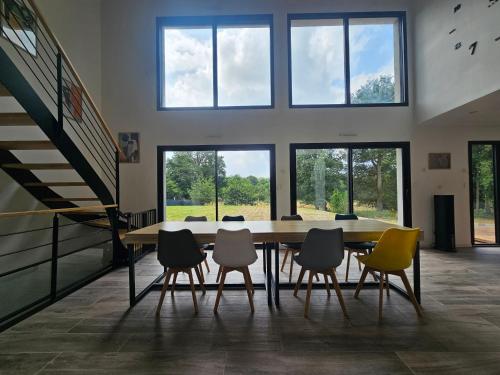 a table and chairs in a room with windows at Les Quatre Baies in Guichen