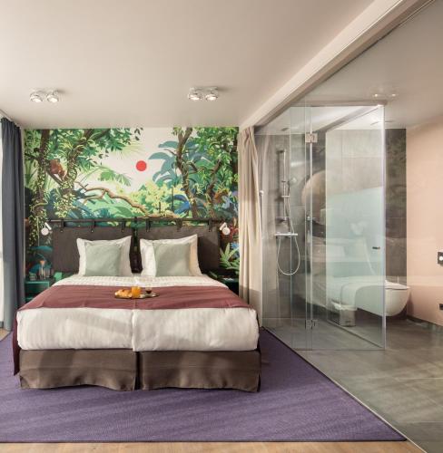 a bedroom with a large bed and a bathroom at Cortile Hotel - Adults Only in Budapest