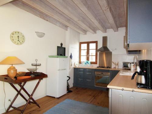 a kitchen with a table and a clock on the wall at Very nice cottage with studio on a domain with heated pool in Roussines