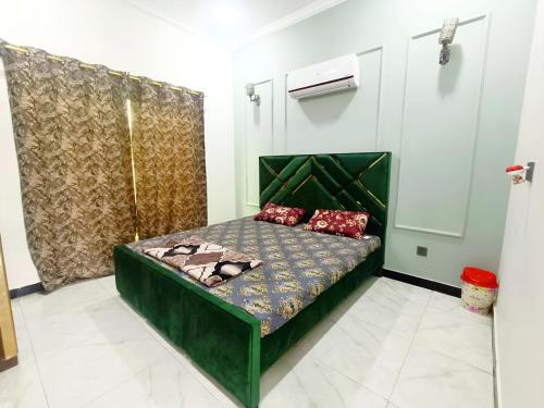 ein Schlafzimmer mit einem grünen Bett mit roten Kissen in der Unterkunft Luxurious Villa in Bahria Town Karachi in Karatschi