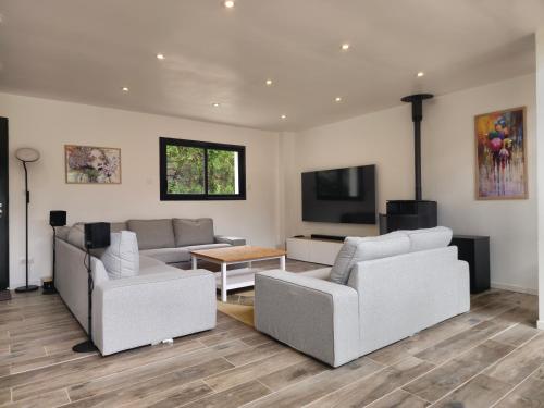 a living room with two couches and a tv at Les Quatre Baies in Guichen