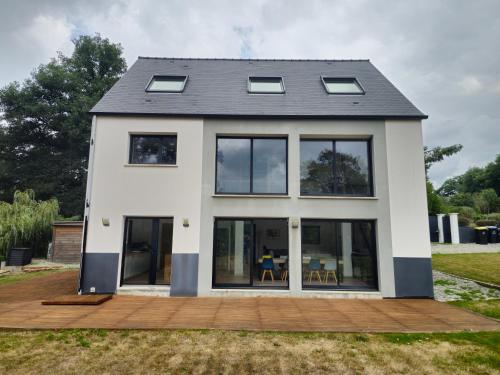 a house with large windows on a deck at Les Quatre Baies in Guichen
