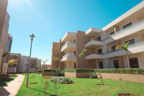 a large apartment building with a lawn in front of it at Appart luxueux Marina Saïdia Tamaris 6 piscines in Saidia 