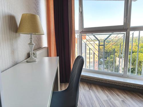 a table with a lamp and a chair next to a window at Stunning new design apartment next to park in Chişinău