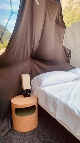 a bed in a tent with a lamp on a table at Bubble Room Gran Paradiso in Noasca