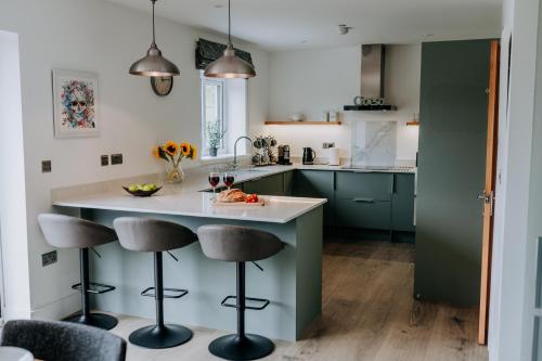 a kitchen with green cabinets and a counter with stools at A Spacious Countryside Retreat for up to 16 Guests in Llanarthney