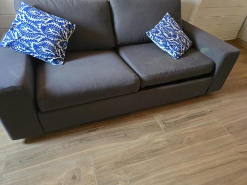 a brown couch with two blue pillows on it at Zimmer Belev HaKikar- Dead sea in Neʼot HaKikar
