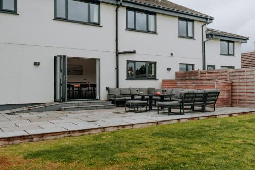 a patio with chairs and a table in front of a house at A Spacious Countryside Retreat for up to 16 Guests in Llanarthney