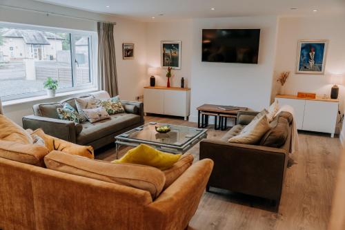 a living room with couches and a large window at A Spacious Countryside Retreat for up to 16 Guests in Llanarthney