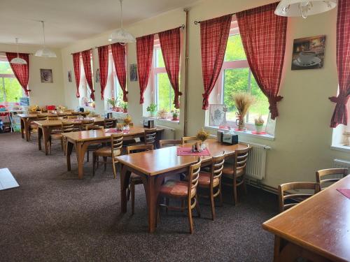 een restaurant met houten tafels en stoelen en ramen bij Pension U Koupaliště in Tisá