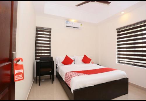 a bedroom with a bed with red pillows and a desk at Better Inn in Cochin
