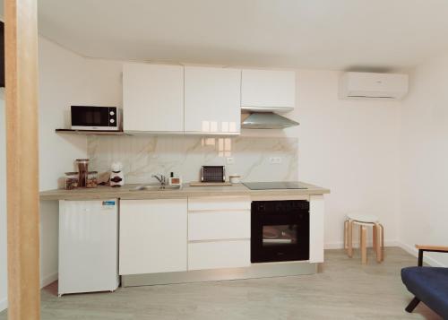 a kitchen with white cabinets and a stove top oven at Casinha do Douro, Cinfães in Escamarão