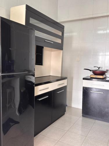 a kitchen with black cabinets and a black refrigerator at Sri Sayang sunset 2 bedroom in Batu Ferringhi
