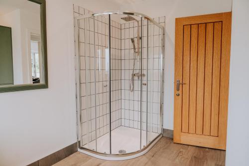 a shower with a glass door in a room at A Spacious Countryside Retreat for up to 16 Guests in Llanarthney