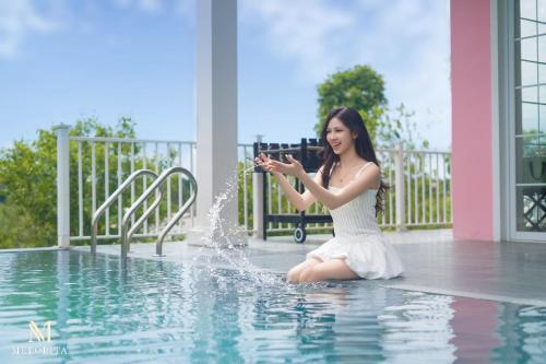 a woman in a white dress sitting in a pool at M-Stay Thạch Thất Hà Nội in Ðào Lãng