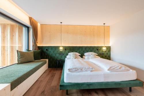 a bedroom with a large bed and a couch at Dolomites Nature Hotel Vigilerhof in Siusi