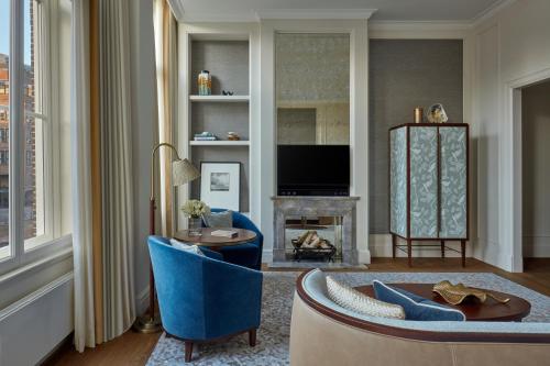 a living room with a blue couch and a fireplace at Waldorf Astoria Amsterdam in Amsterdam