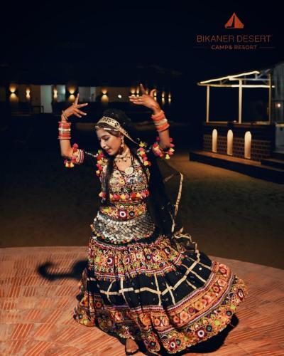 a woman in a dress dancing on the floor at Bikaner Desert Camp and Resort in Bikaner