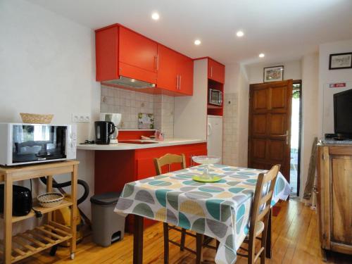 une cuisine avec des placards rouges et une table avec des chaises dans l'établissement La maisonnette a la caze, à Saint-Pierre-des-Tripiers