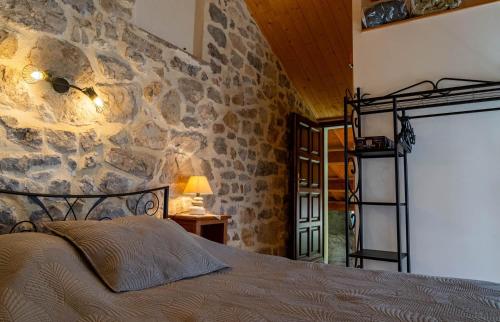 un lit dans une chambre avec un mur en pierre dans l'établissement La maisonnette a la caze, à Saint-Pierre-des-Tripiers