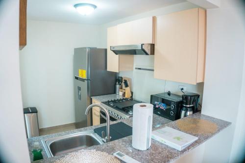 Una pequeña cocina con fregadero y refrigerador. en Peach Haven 143, en San Juan Opico