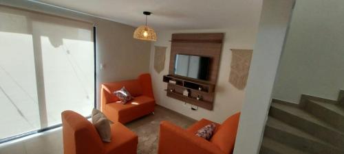 sala de estar con sillas de color naranja y TV en Peach Haven 143, en San Juan Opico