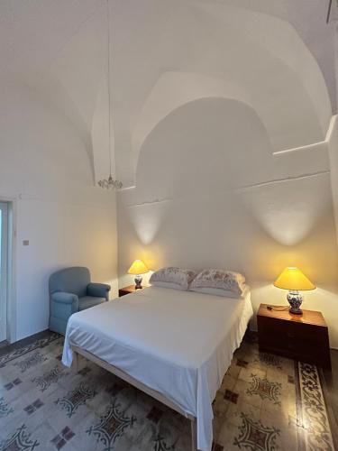 a bedroom with a white bed and a blue chair at Domus Donata in Galatone