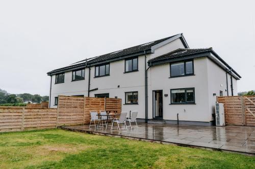 a white house with a patio and a fence at A Spacious Countryside Retreat for up to 16 Guests in Llanarthney