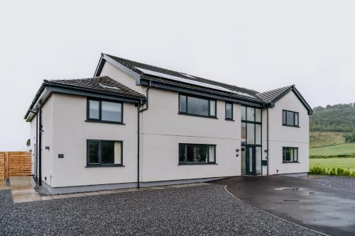 a white house with black windows and a driveway at A Spacious Countryside Retreat for up to 16 Guests in Llanarthney