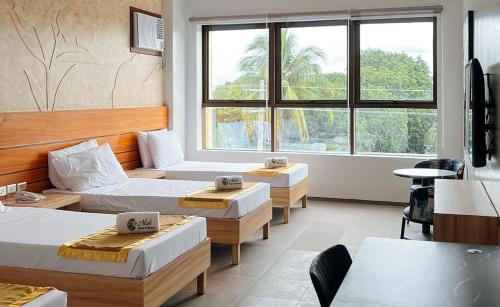 a hotel room with three beds and a window at RedDoorz Plus at Nick Hotel Guimba in Guimba