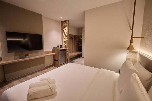 a hotel room with a bed and a flat screen tv at Unya Hotel Ubon - โรงเเรมอัญญาอุบล in Ban Na Khwai