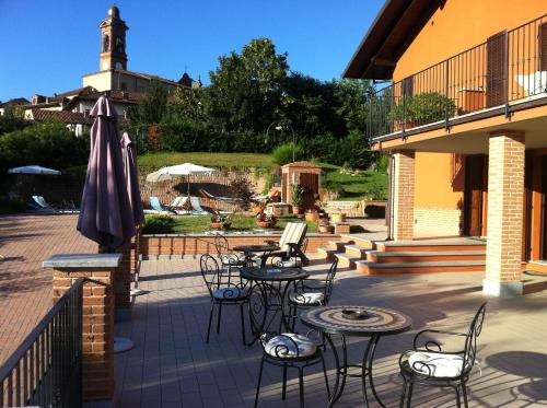 d'une terrasse avec des tables, des chaises et un parasol. dans l'établissement B&B Castelvecchio, à Ferrere